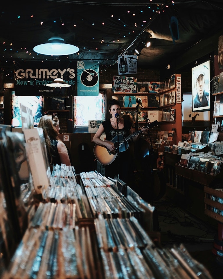 Woman performing live acoustic guitar performance in record store.