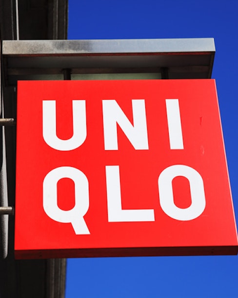 Image showing bright red Uniqlo brand sign against a blue sky and brick wall